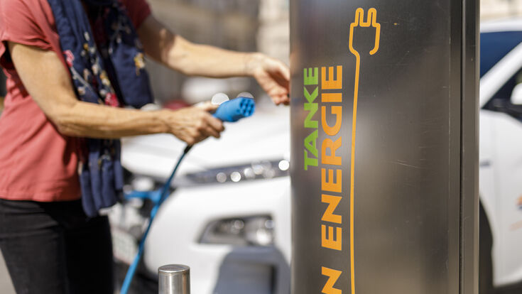 © Wien Energie/FOTObyHOFER Eine Person, die den Tankstecker einer Wien Energie Tankstelle gerade an- oder absteckt, im Hintergrund ein Auto.
