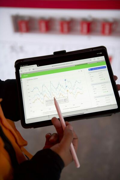 © Schneider Electric Eine Person, die ein Tablet hält, auf dem Temperaturkurven aus EcoStruxure angezeigt werden.