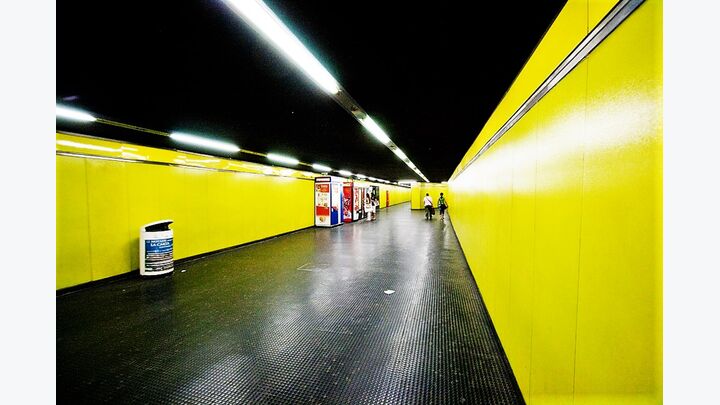 Mailänder U-Bahn-Gang mit gelben Seitenwänden und dunkelgrauer Decke und Boden.