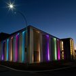 Gebäude im Dunklen von außen: Außenlichter werfen bunte Strahlen über die Häuserfassade.