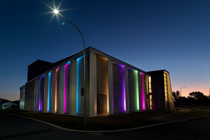 Gebäude im Dunklen von außen: Außenlichter werfen bunte Strahlen über die Häuserfassade.