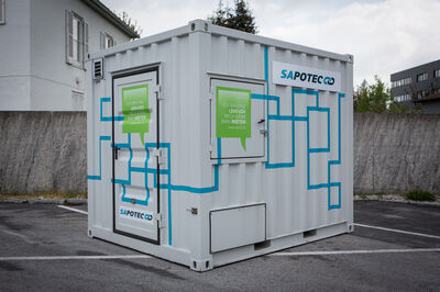 © Sapotec/stefan zauner Eine USV-Anlage in einem weißen Container auf einem Parktplatz.