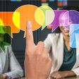 Drei Personen im Gespräch, über die runde und eckige bunte Felder gelegt sind, welche von einer Hand bedient werden.