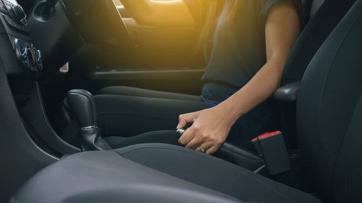 Hand woman driver pulling the hand brake inside modern car